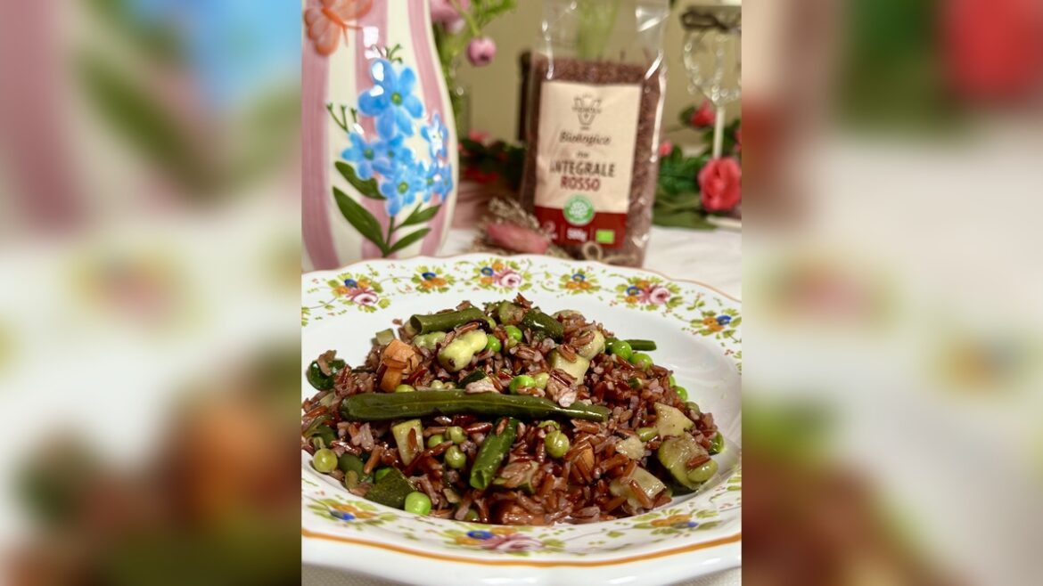 Riso rosso integrale biologico Vignola con zucchine, piselli, fagiolini e fave, in piatto fiorato con confezione sullo sfondo