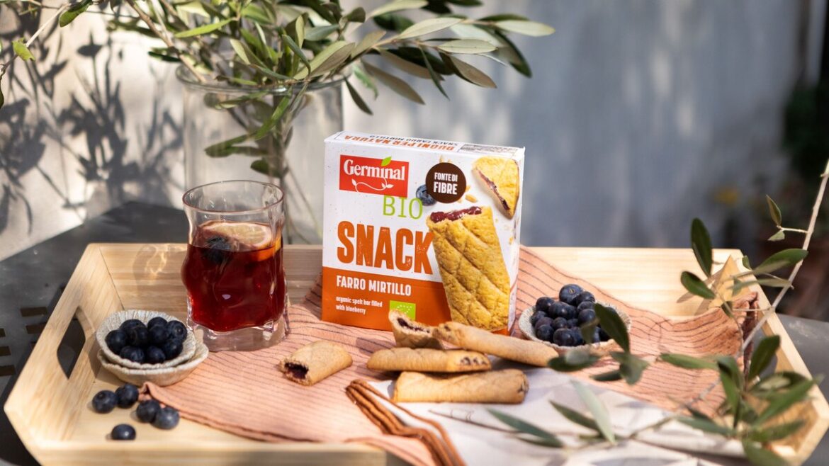 I nuovi snack Buoni per Natura di Germinal Bio al farro e mirtillo: confezione, biscotti farciti e mirtilli freschi su vassoio di legno