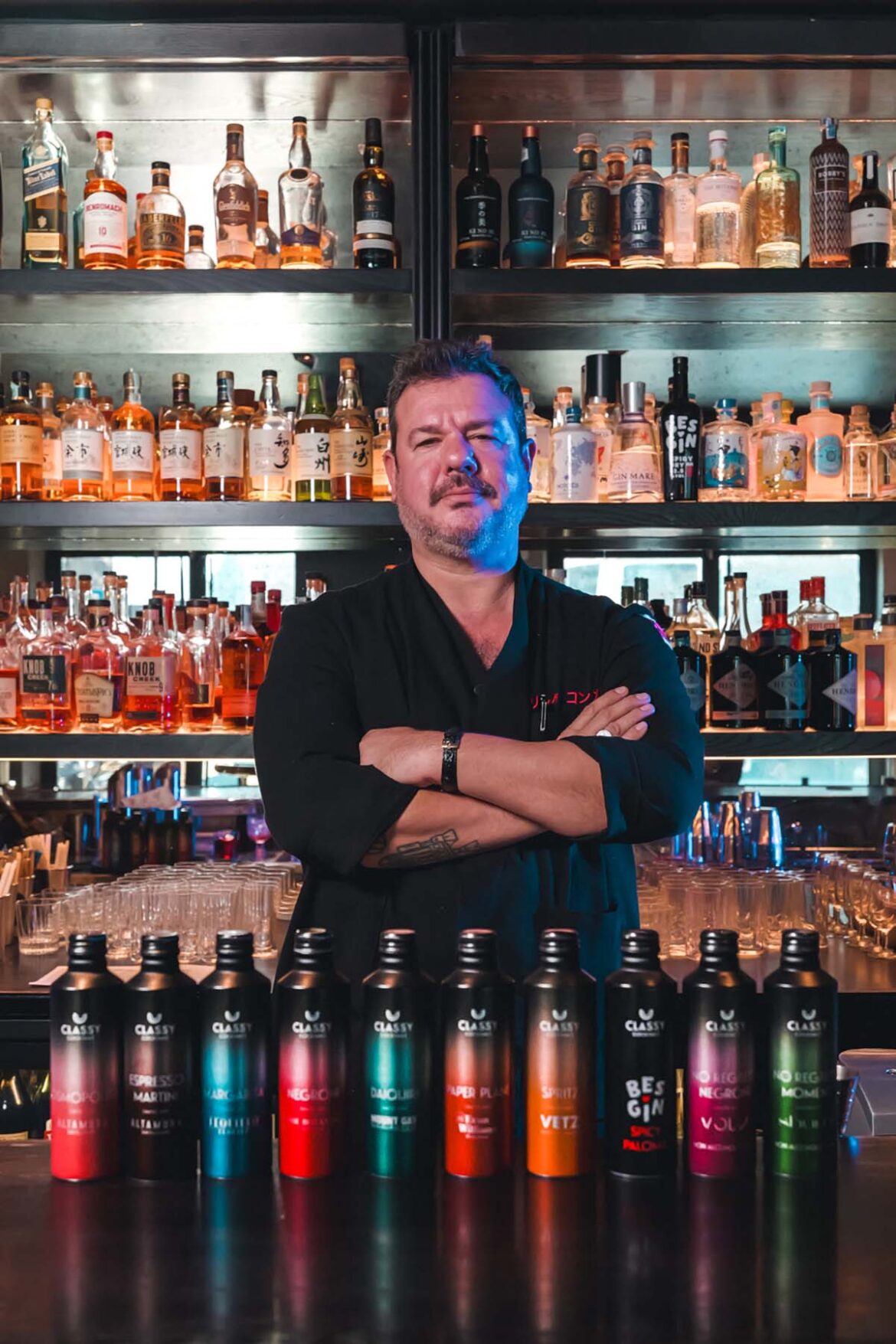 Patrick Pistolesi con le bottiglie Classy Cocktails al bancone del bar