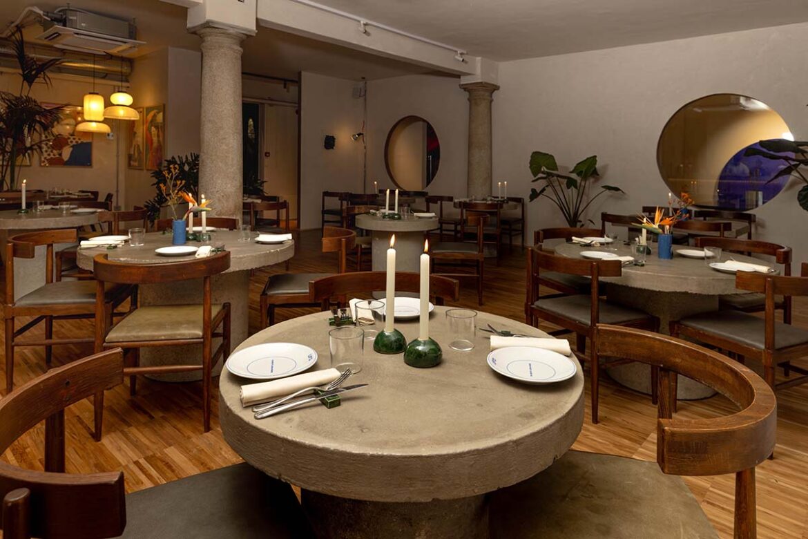 Gli interni di UFO Bistrot a Milano, con i tavoli rotondi in cemento e i grandi oblò circolari