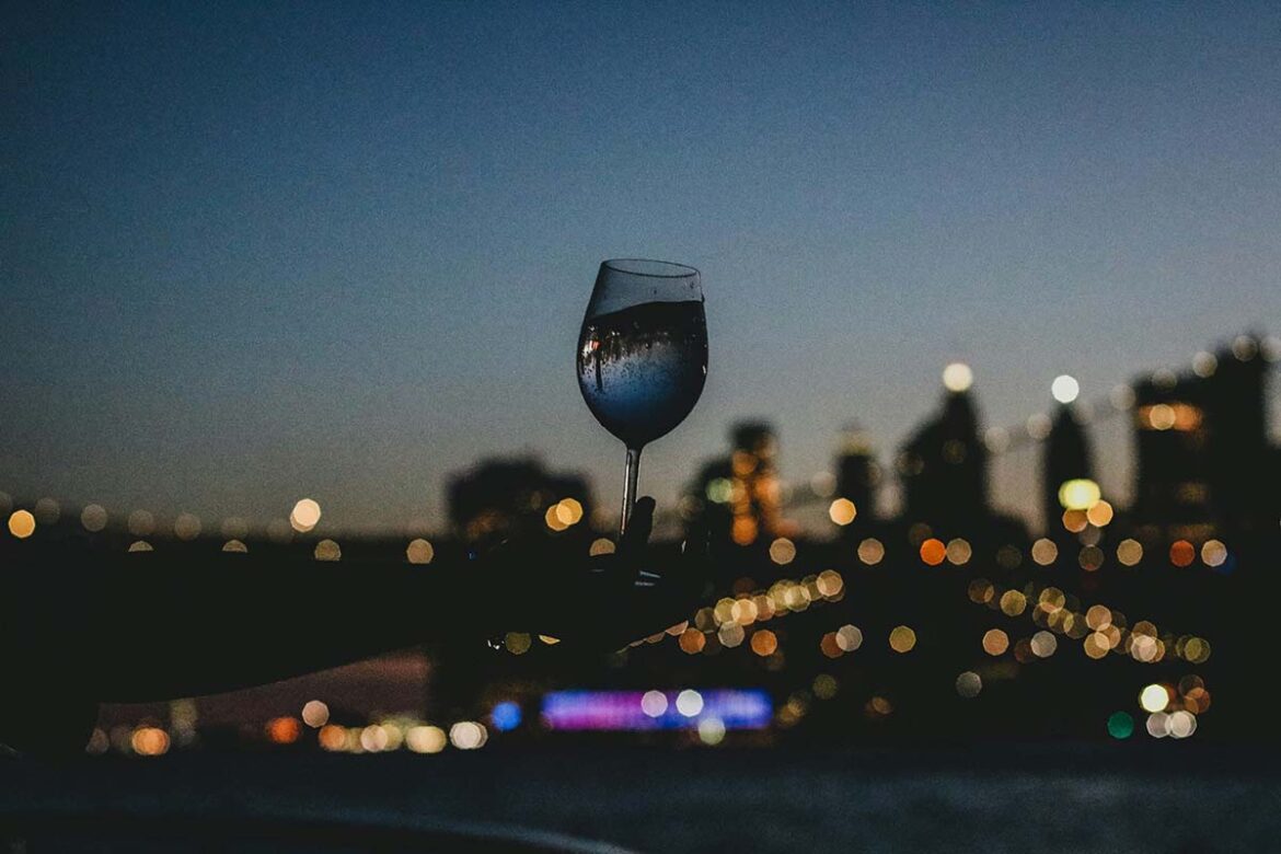 Bicchiere di vino illuminato di notte che racconta Milano capitale del vino
